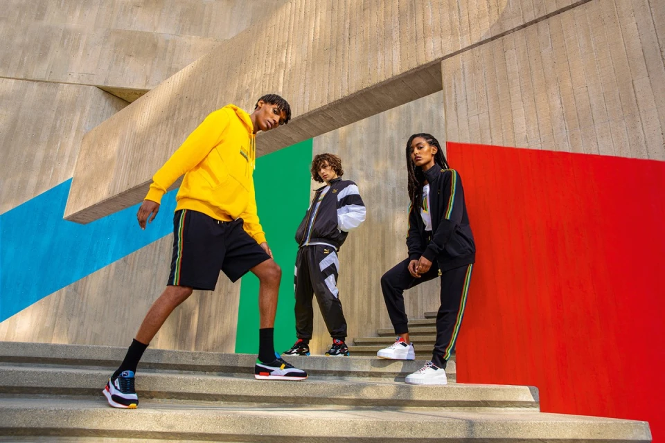 Three athletic adults posing on stairs in black and yellow Puma tracksuits in an urban setting with bright colorful background panels.