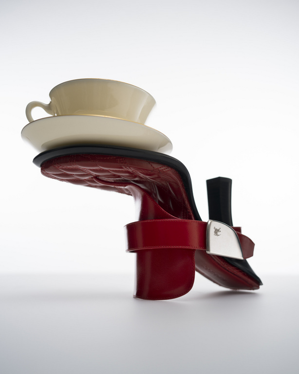 Elegant composition featuring a high heel shoe supporting a teacup and saucer, creating a striking balance of fashion and tableware.