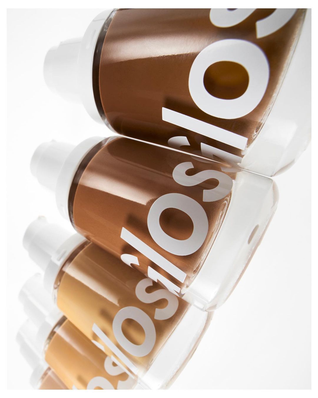 Cosmetic foundation bottles in a row with various shades, showcasing makeup and beauty products, set against a clean, bright white background.