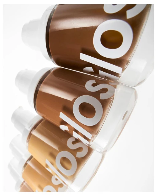 Cosmetic foundation bottles in a row with various shades, showcasing makeup and beauty products, set against a clean, bright white background.