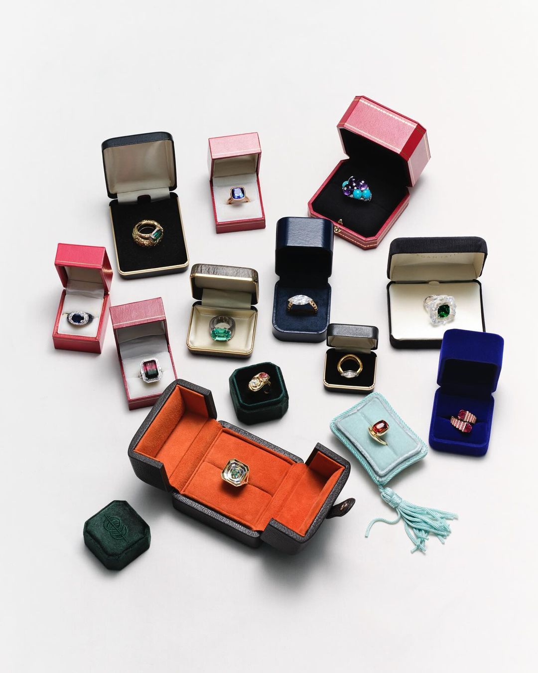 Collection of rings in jewelry boxes of various colours and styles are displayed on a white surface in a product shot.