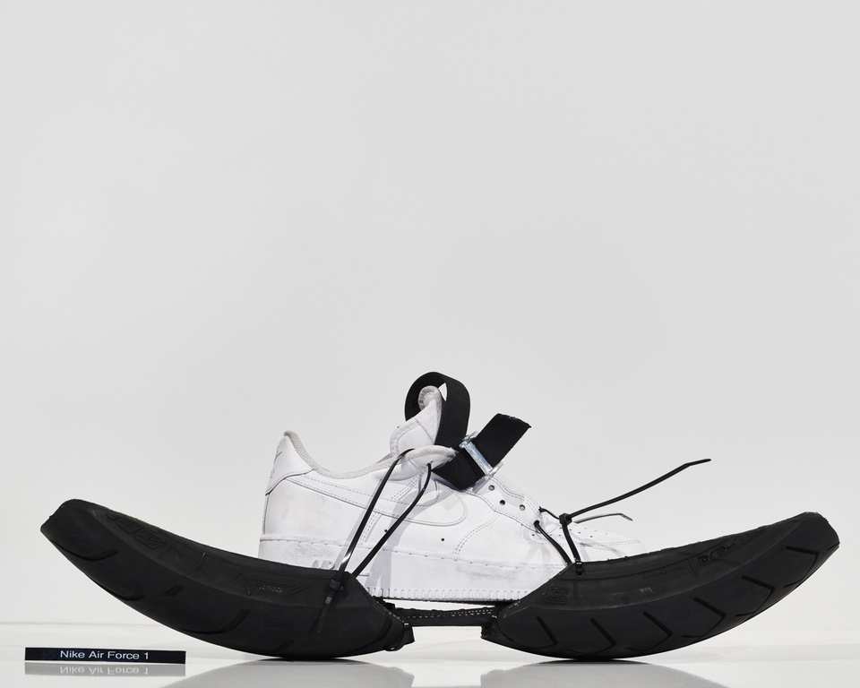 Nike Air Force 1 sneaker with custom black tire tread sole. Studio shot with white background. Fashionable footwear product.