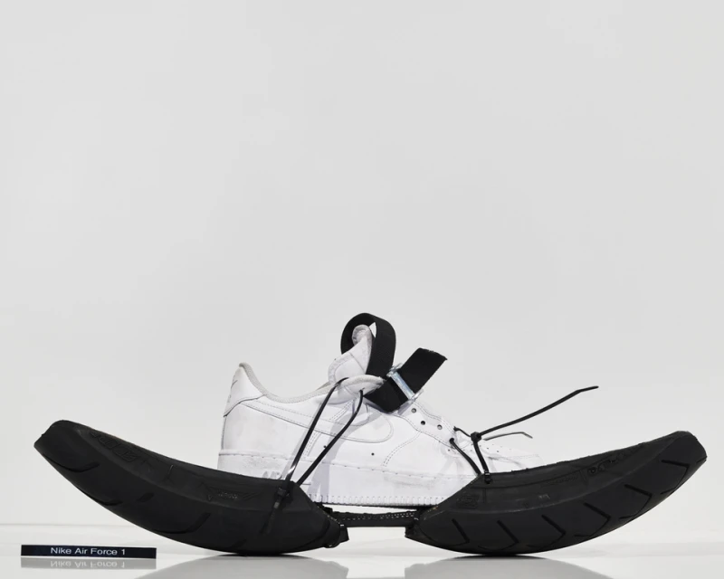 Nike Air Force 1 sneaker with custom black tire tread sole. Studio shot with white background. Fashionable footwear product.