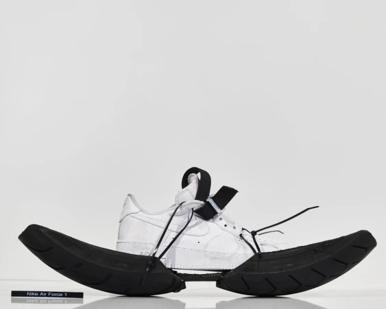 Nike Air Force 1 sneaker with custom black tire tread sole. Studio shot with white background. Fashionable footwear product.