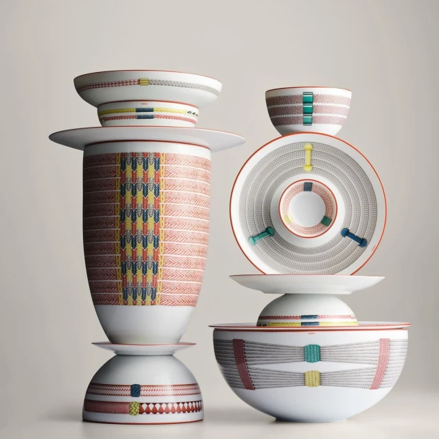 Stack of ceramic bowls, plates, and vase featuring colorful decorative geometric patterns displayed against a neutral background.