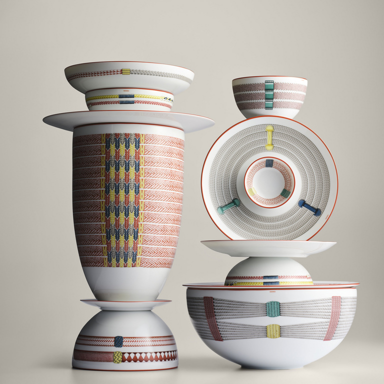 Stack of decorative porcelain dinnerware, including bowls and plates with geometric designs, against a pale neutral background.