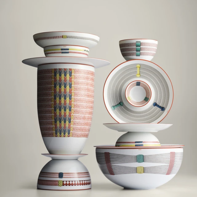 Stack of decorative porcelain dinnerware, including bowls and plates with geometric designs, against a pale neutral background.