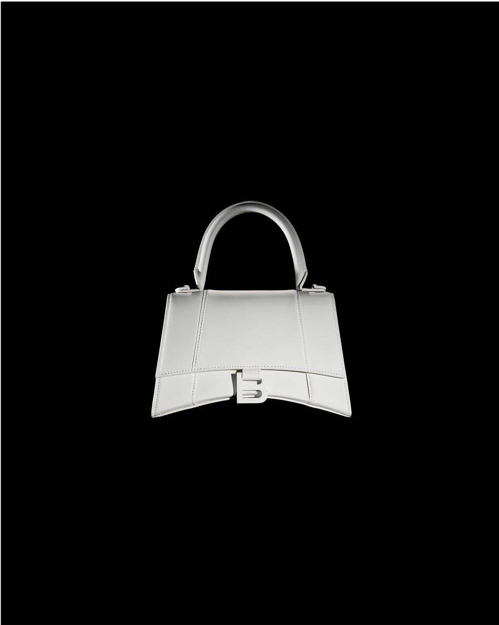Silver Balenciaga handbag isolated on a stark black background, showcasing its trapezoidal design, handle, and the distinctive B logo.
