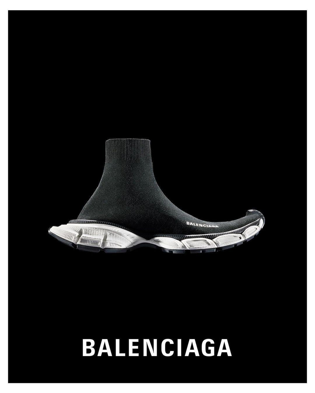 Black Balenciaga sock-style sneaker with white sole on black background. High-fashion footwear, athletic shoe, studio shot.