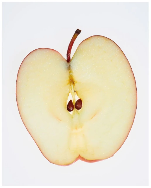 Close-up of a halved red apple on a white background, showcasing its seeds, stem, and the juicy interior of the fruit.