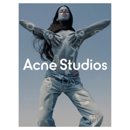 Woman poses with body paint and jeans in a studio shot, showcasing a fashion-forward look with visible branding and peace symbols.