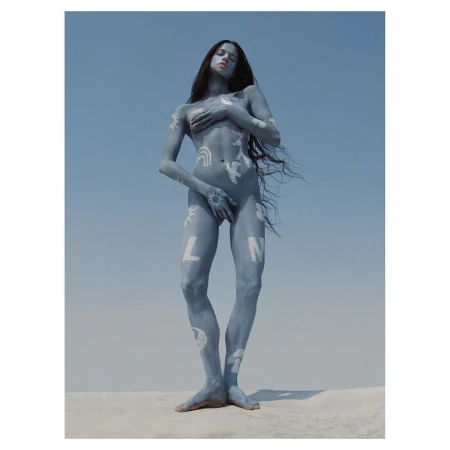 Nude female with body paint stands against a blue sky backdrop, creating a striking and artistic outdoor portrait with long hair.