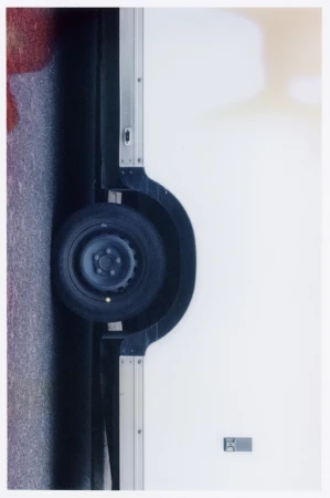 Automotive scene featuring a tire mounted on a white truck body, set against a gray road, showcasing details of vehicle design.