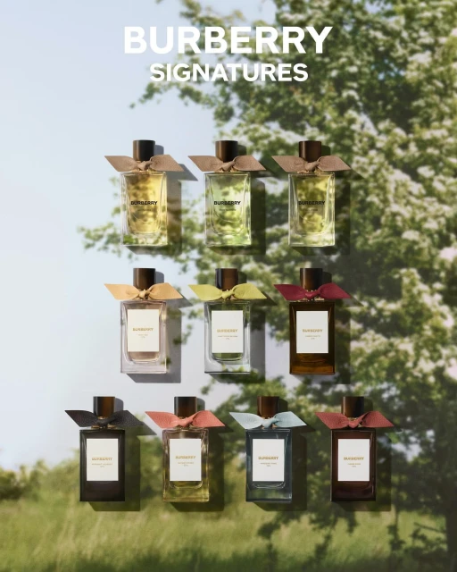 Burberry Signatures fragrance collection featuring nine glass perfume bottles with colorful ribbon accents against an outdoor backdrop.