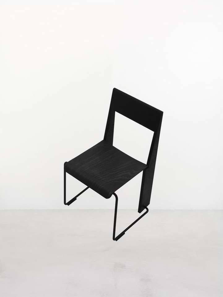 Modern black chair with a minimalistic design, showcasing clean lines and an open back against a bright, neutral background.