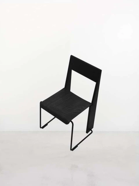 Modern black chair with a minimalistic design, showcasing clean lines and an open back against a bright, neutral background.