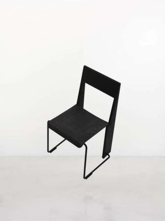 Modern black chair with a minimalistic design, showcasing clean lines and an open back against a bright, neutral background.