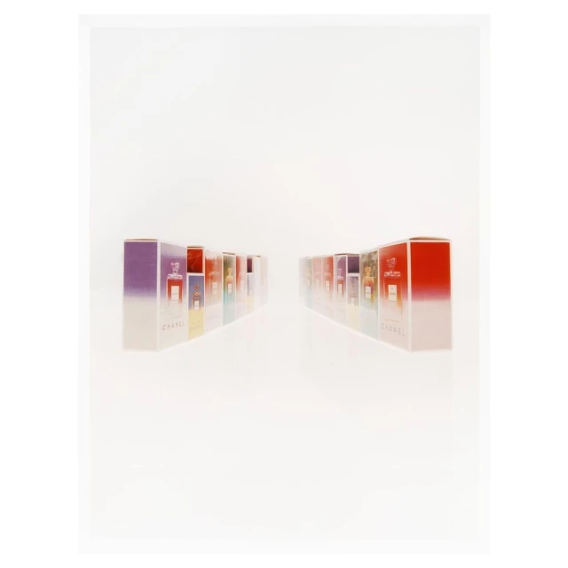 A series of Chanel perfume boxes are displayed on a white surface, arranged in two parallel rows with various colors and sizes.