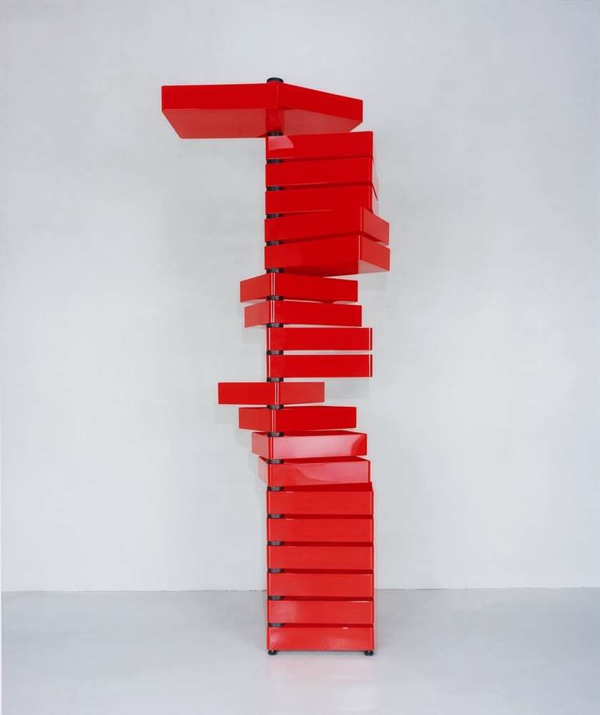 Unique red shelf, chest of drawers with a spiral design, stands in front of a white wall and floor. Perfect for home or design studio.