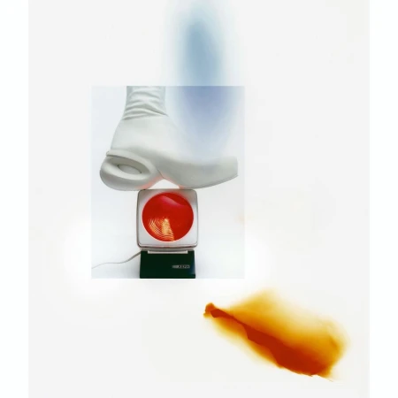 Conceptual shot of a white platform shoe on a red-and-white scale, with a blurred brown form against a bright white backdrop.