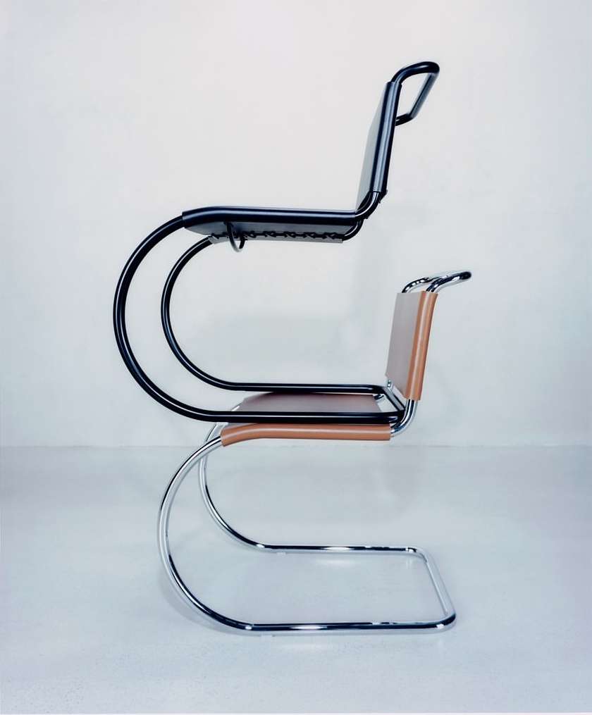 Side view of two cantilever chairs, one black and one tan leather, stacked on top of each other against a light grey backdrop.