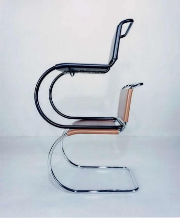 Side view of two cantilever chairs, one black and one tan leather, stacked on top of each other against a light grey backdrop.