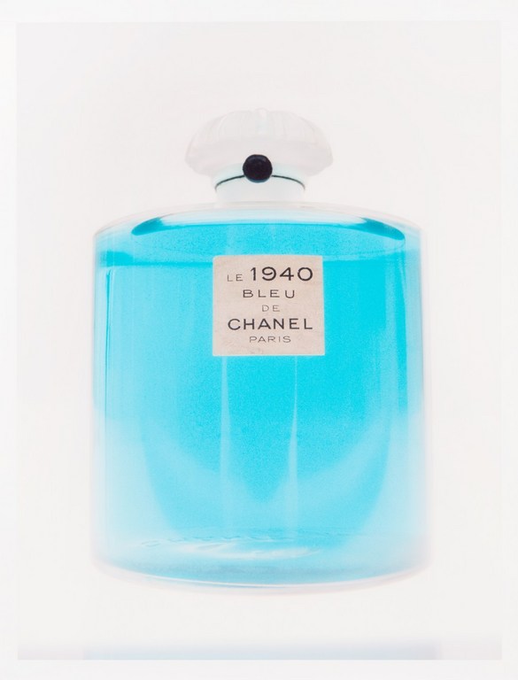 Translucent blue glass perfume bottle with white cap and 'Le 1940 Bleu de Chanel Paris' label against white background.