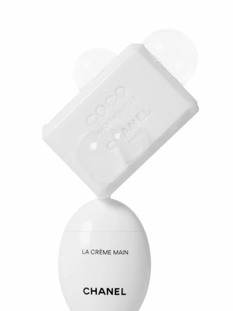 Close-up studio shot of Chanel soap and lotion on a white background with floating bubbles, showcasing beauty and skincare products.