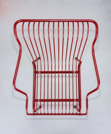 Elevated view of a red painted wire chair featuring an open, linear design on a light grey studio background, creating a minimalist aesthetic.