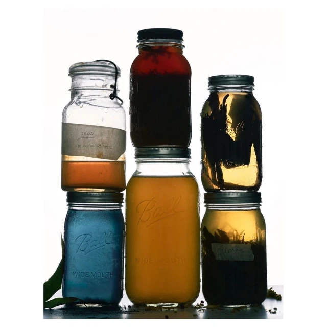 Stacked mason jars filled with colourful liquids, creating a visually appealing display against a bright white background.
