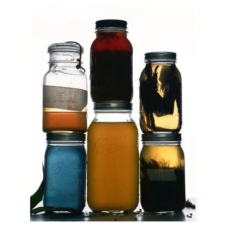 Stacked mason jars filled with colourful liquids, creating a visually appealing display against a bright white background.