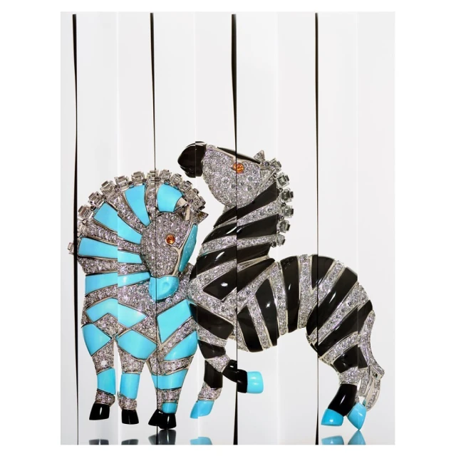 Two decorative zebra sculptures, one black and white stripes and another with turquoise details, stand against white background.
