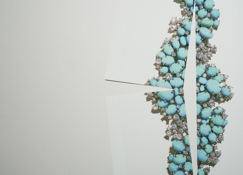 Turquoise and diamond necklace with geometric white paper cutouts on a clean, white background. High-end jewelry with a modern aesthetic.