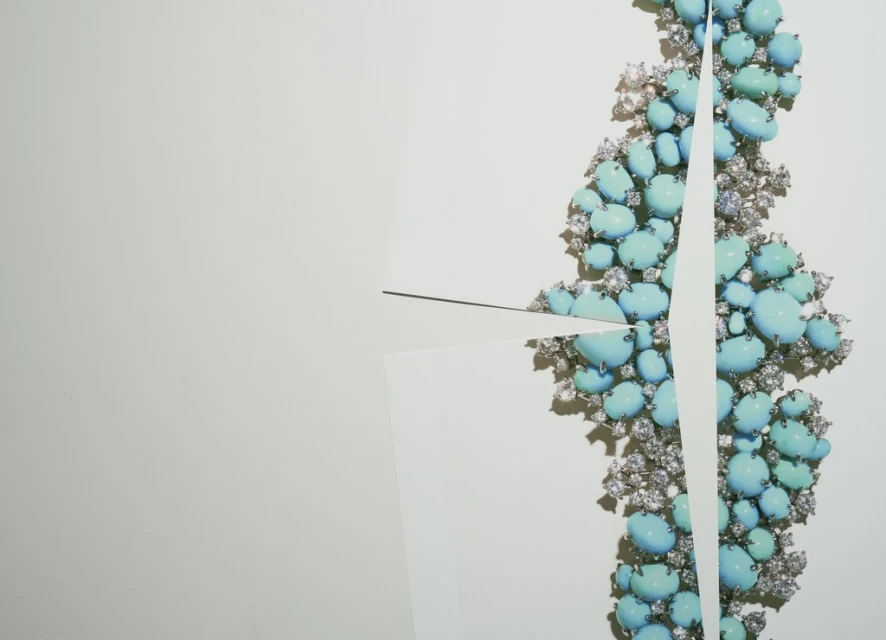 Turquoise and diamond necklace with geometric white paper cutouts on a clean, white background. High-end jewelry with a modern aesthetic.