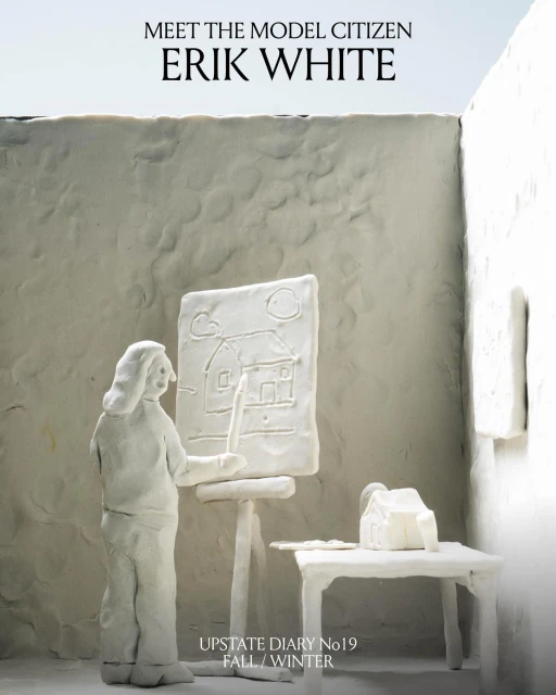 Clay figure of a person painting a house on a canvas in a white room. The person and setting are made of white clay.