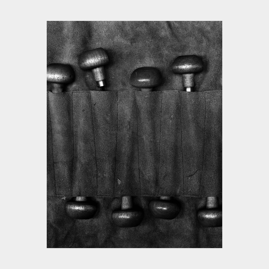 Monochrome image showing a toolkit with round-handled tools neatly arranged in individual slots, tools facing in opposite directions.