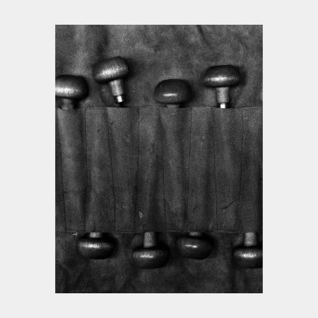 Monochrome image showing a toolkit with round-handled tools neatly arranged in individual slots, tools facing in opposite directions.