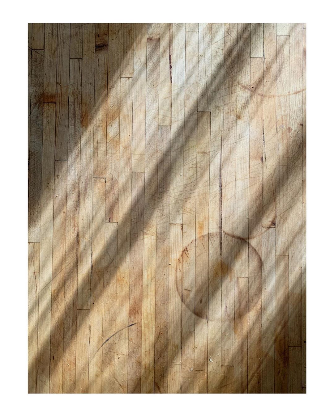 Overhead close-up of a wooden butcher block surface with light streaks, aged appearance, and a visible ring stain.