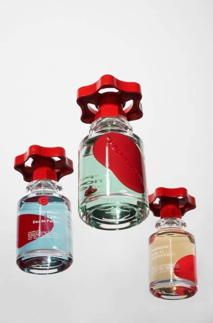 Three Off-White Paperwork Solution perfume bottles with distinctive red valve-style caps are displayed on a white background in a studio shot.