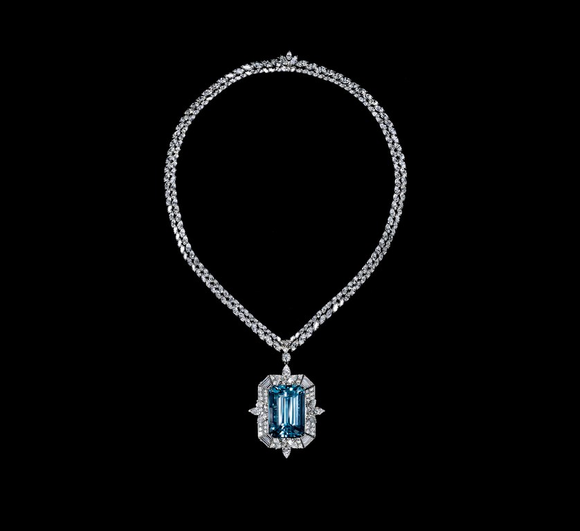 Elegant necklace with a large aquamarine pendant surrounded by diamonds, set against a stark black backdrop to enhance its brilliance.