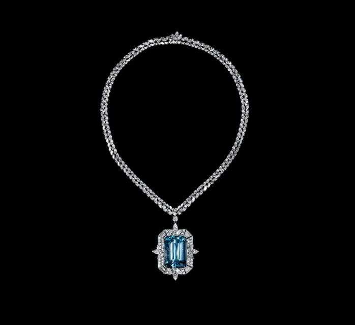 Elegant necklace with a large aquamarine pendant surrounded by diamonds, set against a stark black backdrop to enhance its brilliance.