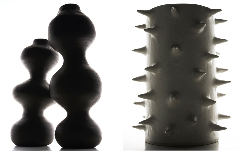 Two dark, smooth vases with curved silhouettes and a white vase with spike-like protrusions in a studio with a white backdrop.
