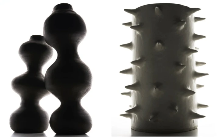 Two dark, smooth vases with curved silhouettes and a white vase with spike-like protrusions in a studio with a white backdrop.