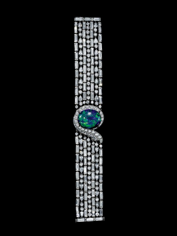 Stunning bracelet on black: brilliant-cut diamonds, rectangular stones, an oval opal center, and a snake design. Jewelry perfection.