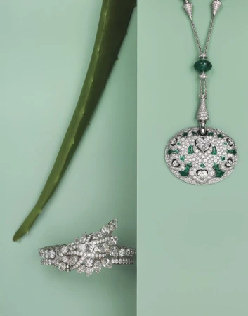 An overhead shot showcases luxury jewelry: a necklace and bracelet featuring diamonds and emeralds, alongside an aloe vera leaf on a light green surface.