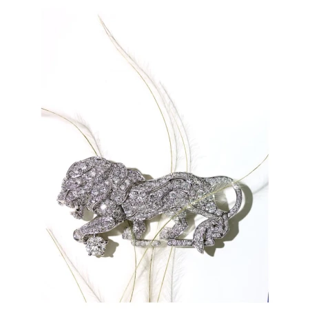 Diamond lion brooch resting among delicate white feathers against a clean white background