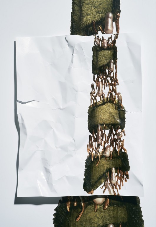 Abstract still life with crumpled white paper, mossy blocks, and copper-toned decorative elements, creating an artful, textural composition.