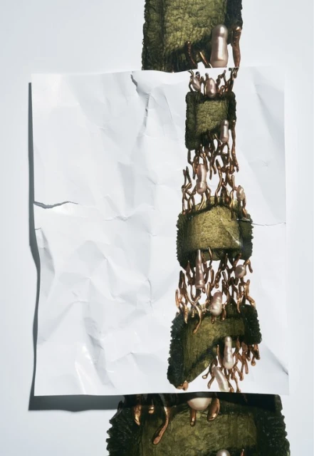 Abstract still life with crumpled white paper, mossy blocks, and copper-toned decorative elements, creating an artful, textural composition.