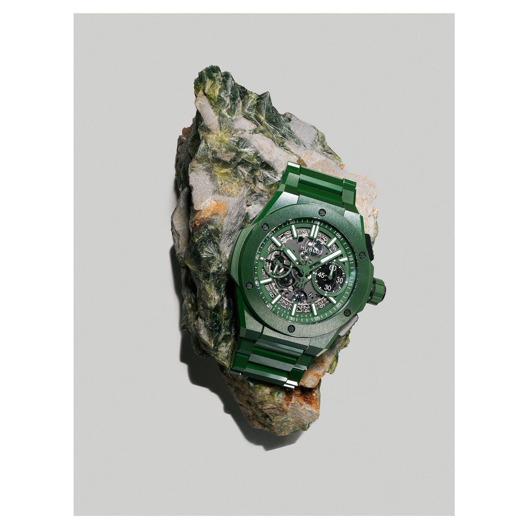 Green skeleton wristwatch on a textured rock, highlighting luxury timekeeping against a natural stone backdrop in a studio setting.