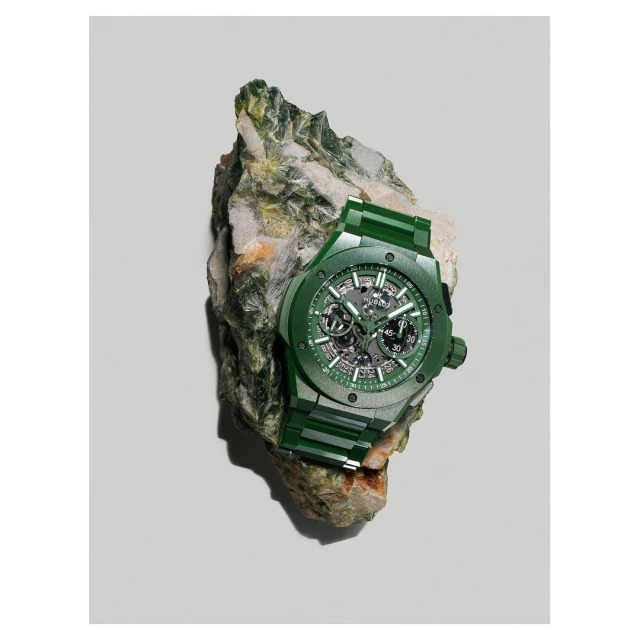 Green skeleton wristwatch on a textured rock, highlighting luxury timekeeping against a natural stone backdrop in a studio setting.